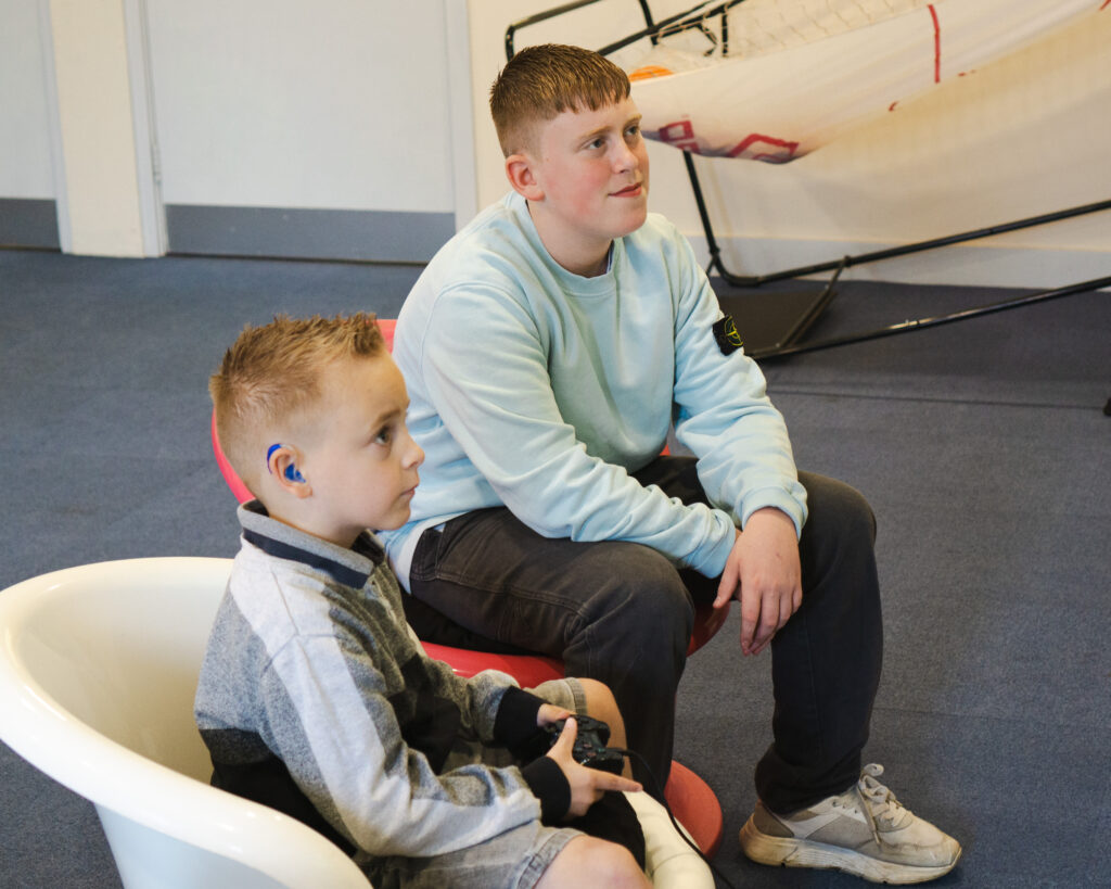 children sat at family contact room playing Play Station