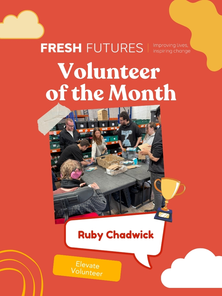 A vibrant recognition poster featuring Ruby Chadwick as 'Volunteer of the Month' for Fresh Futures. The poster has a red-orange background with cloud and swirl graphics. In the centre, a photo shows a group of volunteers working around a table in what appears to be a warehouse or storage area. Ruby Chadwick is highlighted as an 'Elevate Volunteer.' A golden trophy icon adds to the celebratory theme. The top of the poster includes the Fresh Futures logo and the tagline, 'Improving lives, inspiring change.
