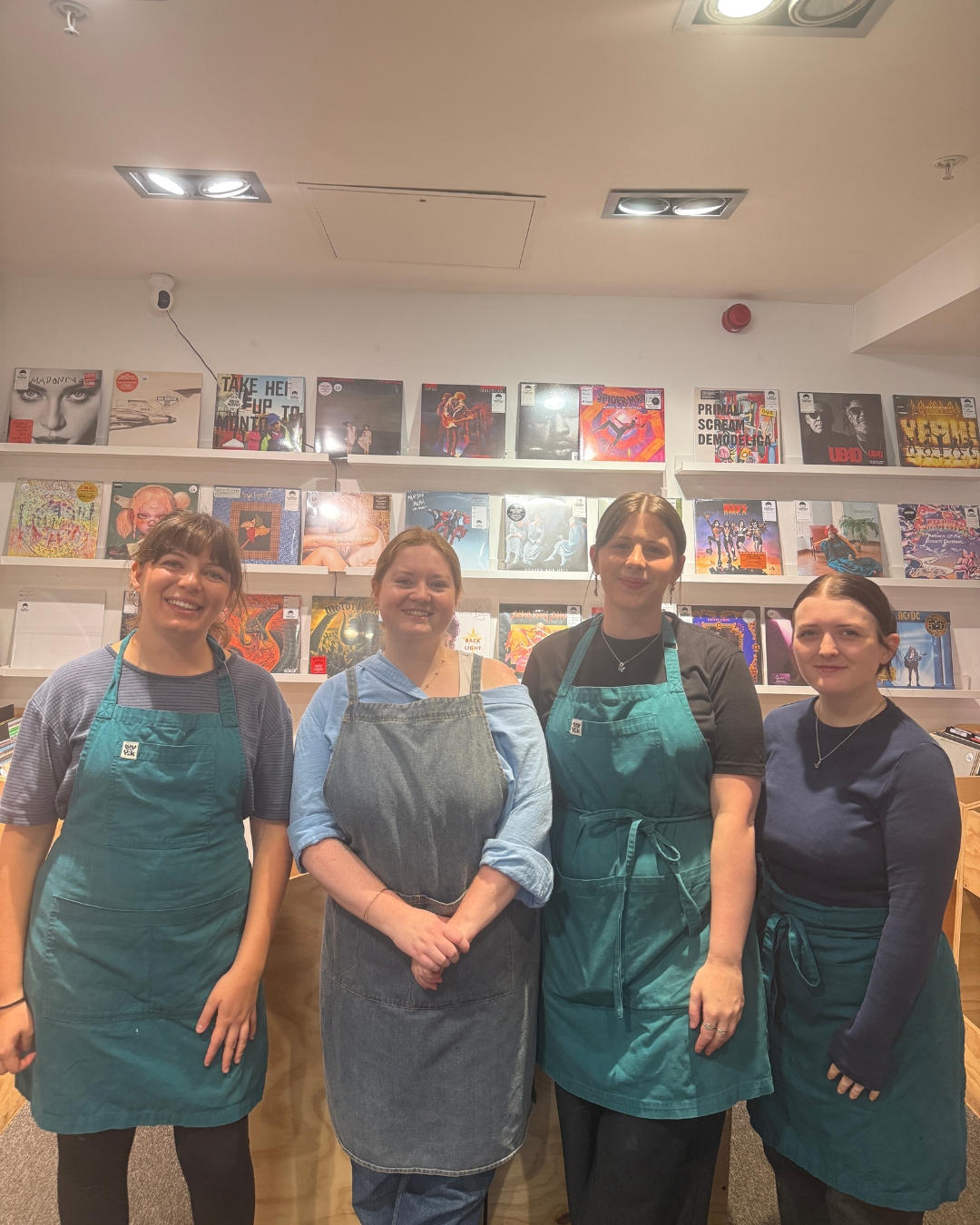Image of 4 female members of staff at Turntable Vinyl Cafe in aprons smiling. 