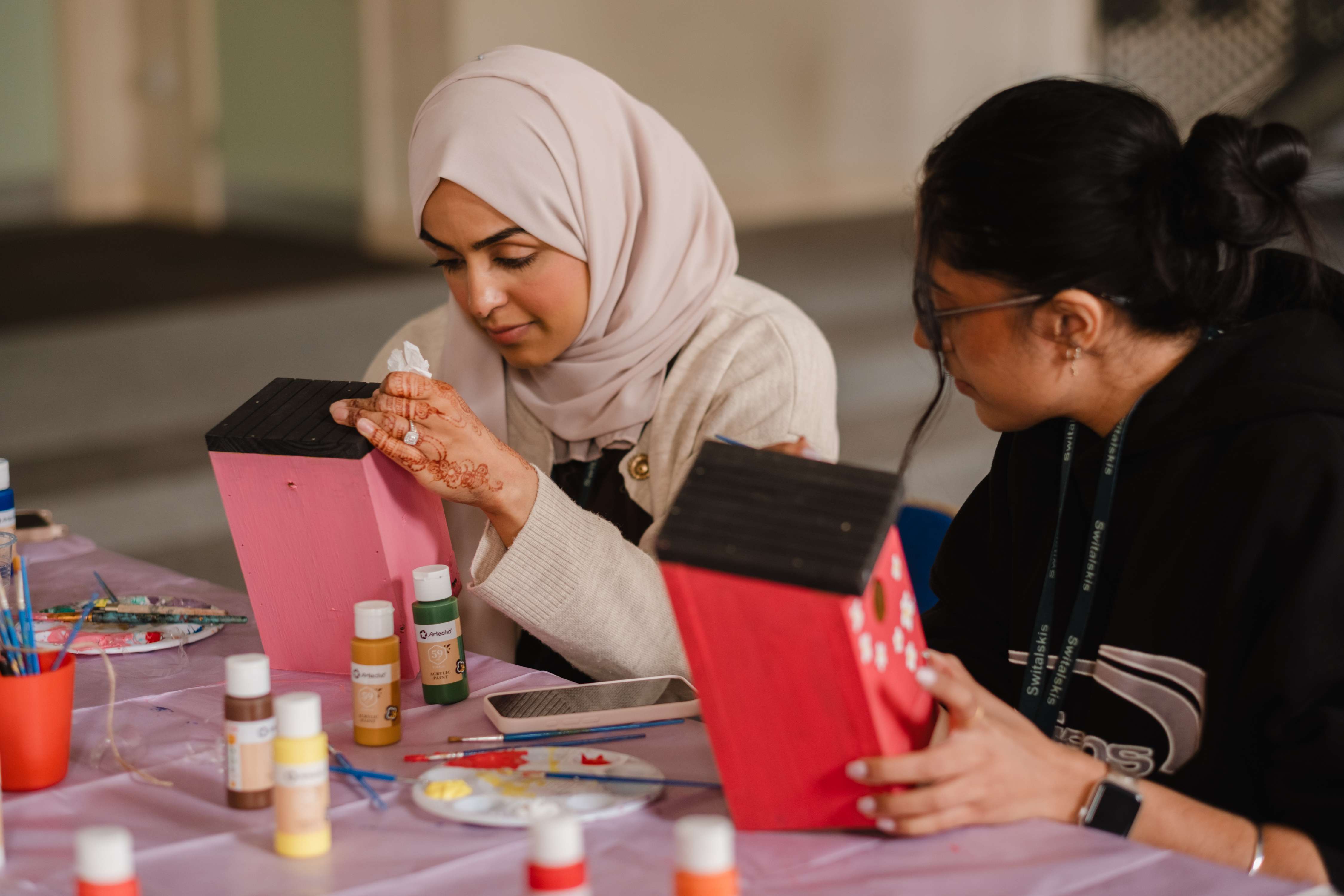volunteers painting birdhouses pink - Picture by Liz Baker Photography