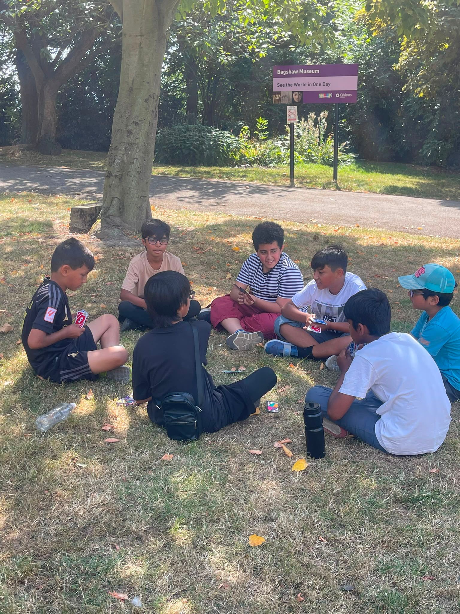 HAF children sat in a circle at a park playing UNO
